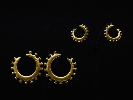 Pair of gold hoop earrings and rings on a black background